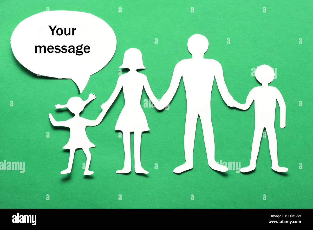 Figure di cartone della famiglia su uno sfondo verde. Il simbolo di unità e di felicità. Le mani abbraccio delicatamente la famiglia. Foto Stock