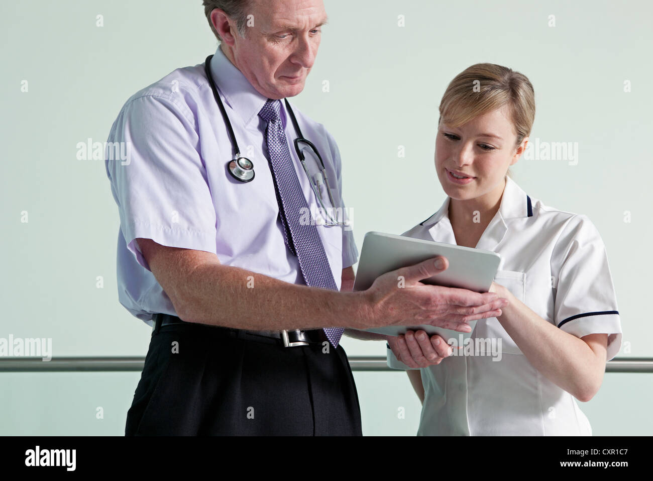 Medico e infermiere discutendo i record medici su tavoletta digitale Foto Stock