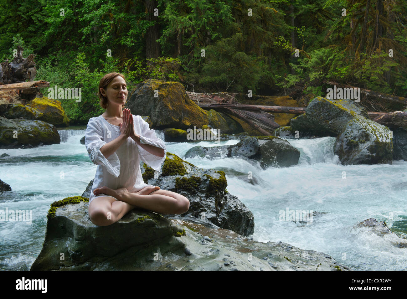 Donna meditando su roccia da acqua Foto Stock