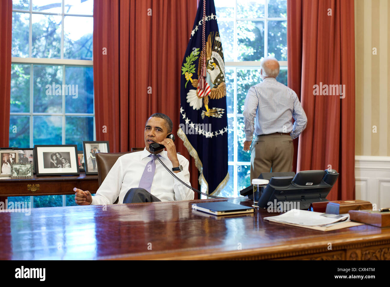 Vice Presidente USA Joe Biden guarda fuori dalla finestra come il Presidente Barack Obama parla al telefono con altoparlante Casa John Boehner all Ufficio Ovale per discutere gli sforzi in atto nel limite del debito e la riduzione del deficit colloqui, Domenica, 31 luglio 2011. Foto Stock