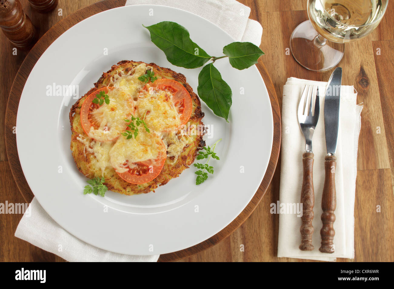 Roesti di patate con fette di pomodoro e formaggio fuso, vino bianco Foto Stock