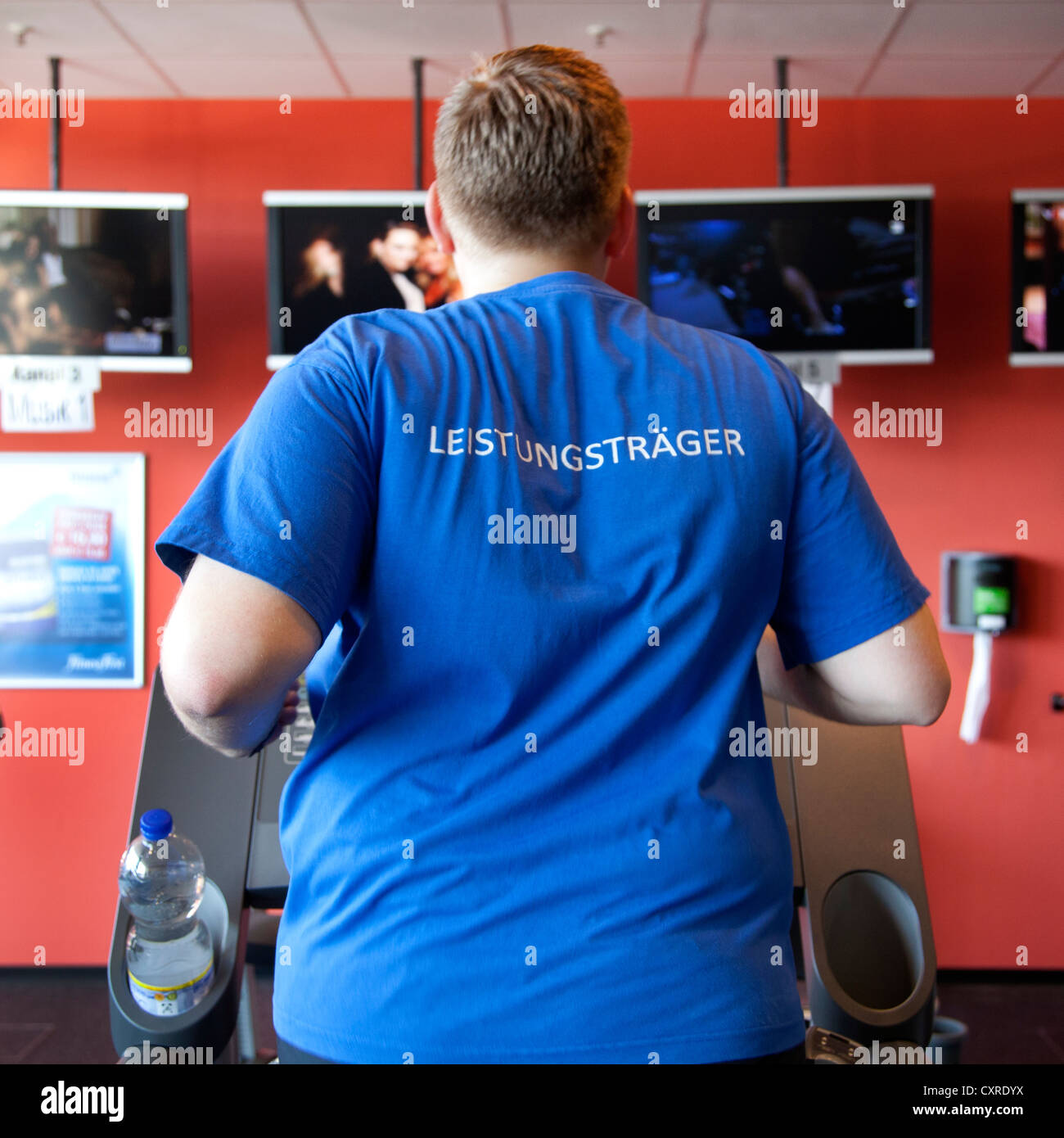 Atleta che indossa una t-shirt, lettering "Leistungstraeger', Tedesco per 'top performer', in esecuzione su un tapis roulant, centro fitness Foto Stock