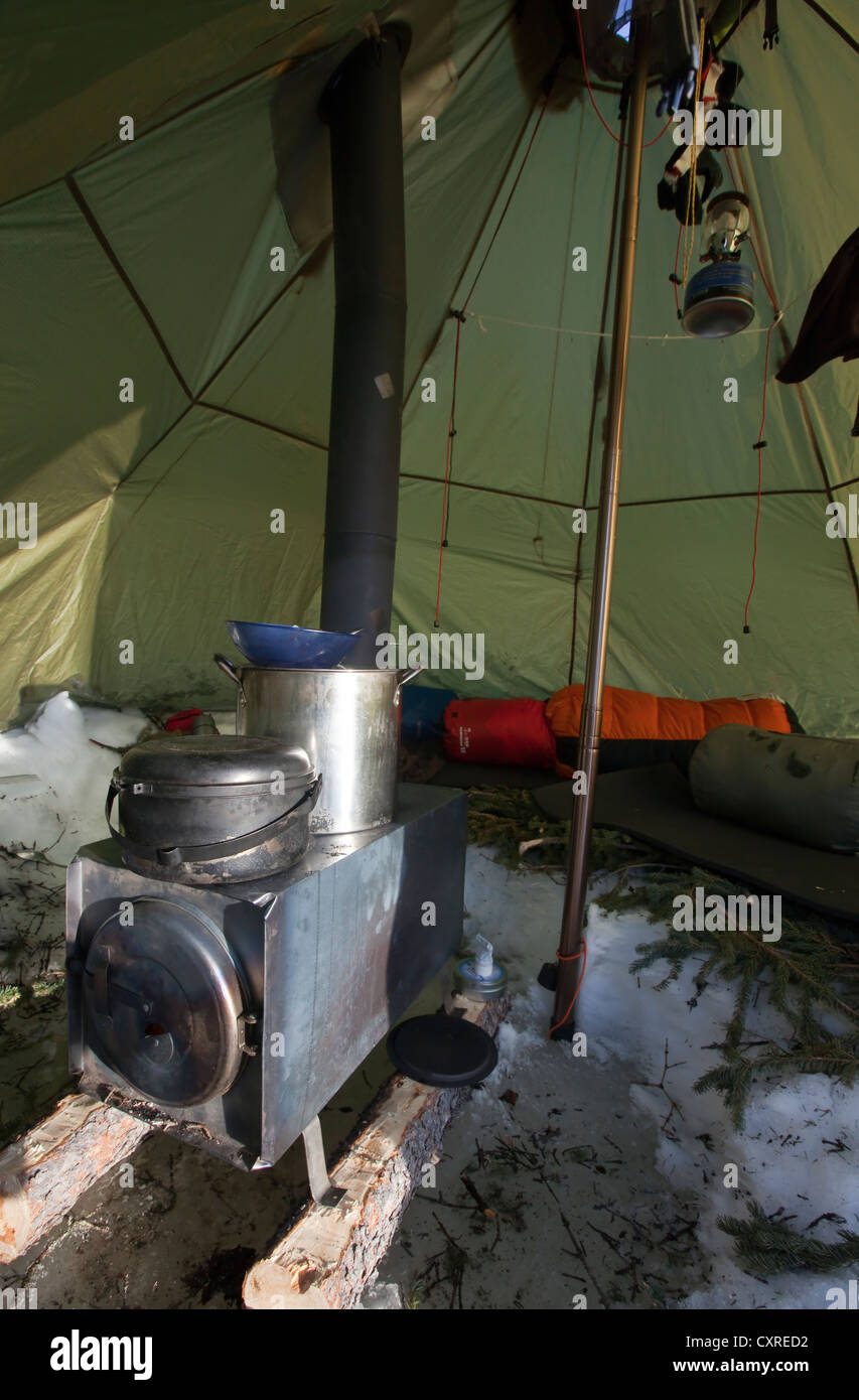 All'interno di un moderno teepee, stufa a legna con pentole, campeggio invernale, Yukon Territory, Canada Foto Stock