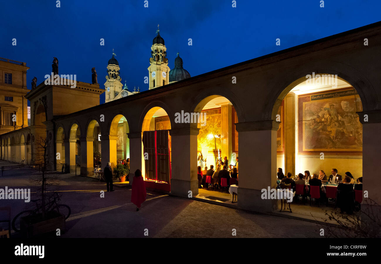 La gente seduta sotto i portici di Luigi Tambosi Cafe su Odeonsplatz piazza Chiesa Theatinerkirche sul retro Foto Stock
