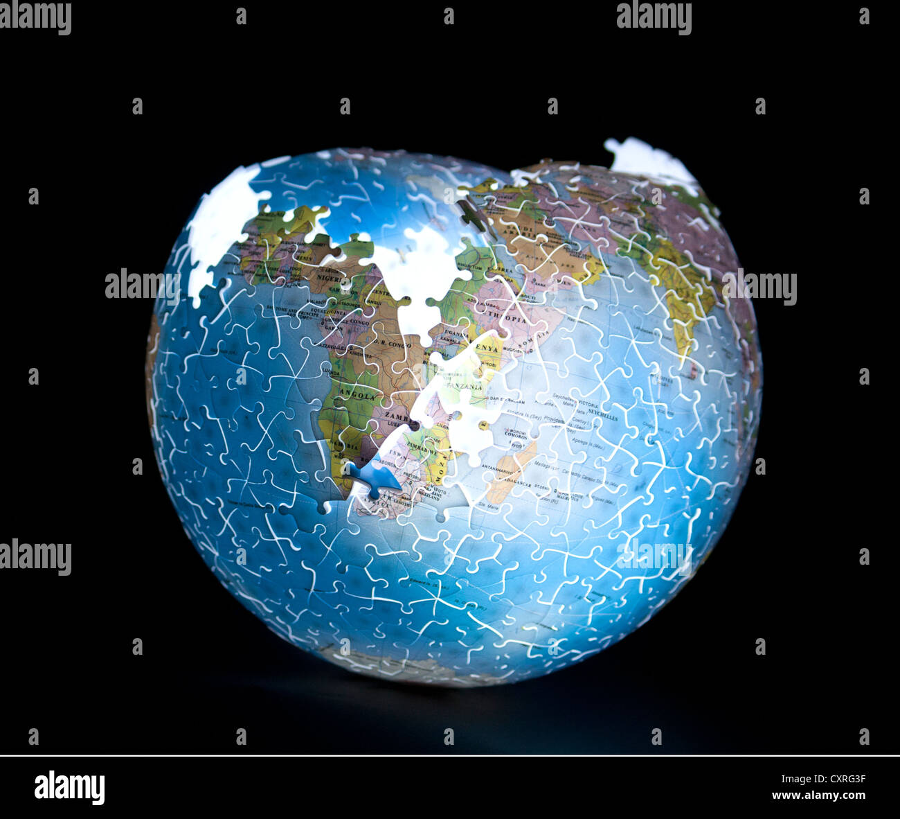 Puzzle globo della terra illuminata internamente, parzialmente completo su sfondo nero Foto Stock