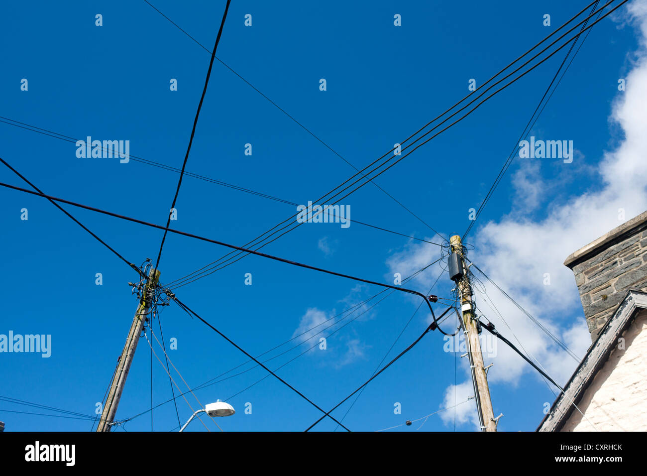 Vista astratta verso l'alto per fili e cavi incrociati su strada con cielo blu sullo sfondo Llanddewi Brefi Galles Ceredigion REGNO UNITO Foto Stock