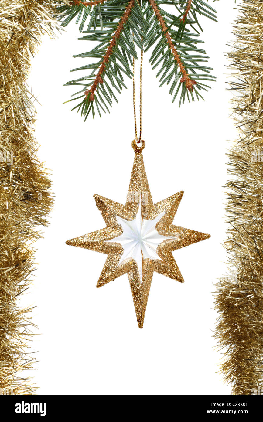 Oro stella di Natale decorazione circondato da tinsel appeso a un albero di Natale ramo Foto Stock