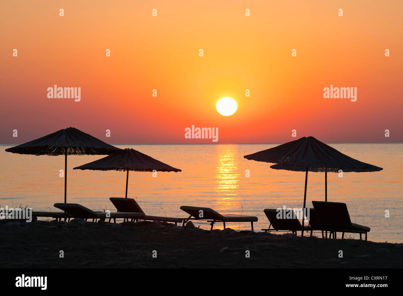 Sedie a sdraio e ombrelloni sulla spiaggia al tramonto, Lycian coast, Lycia, il Mar Egeo e il Mar Mediterraneo, la Turchia, Asia Minore Foto Stock