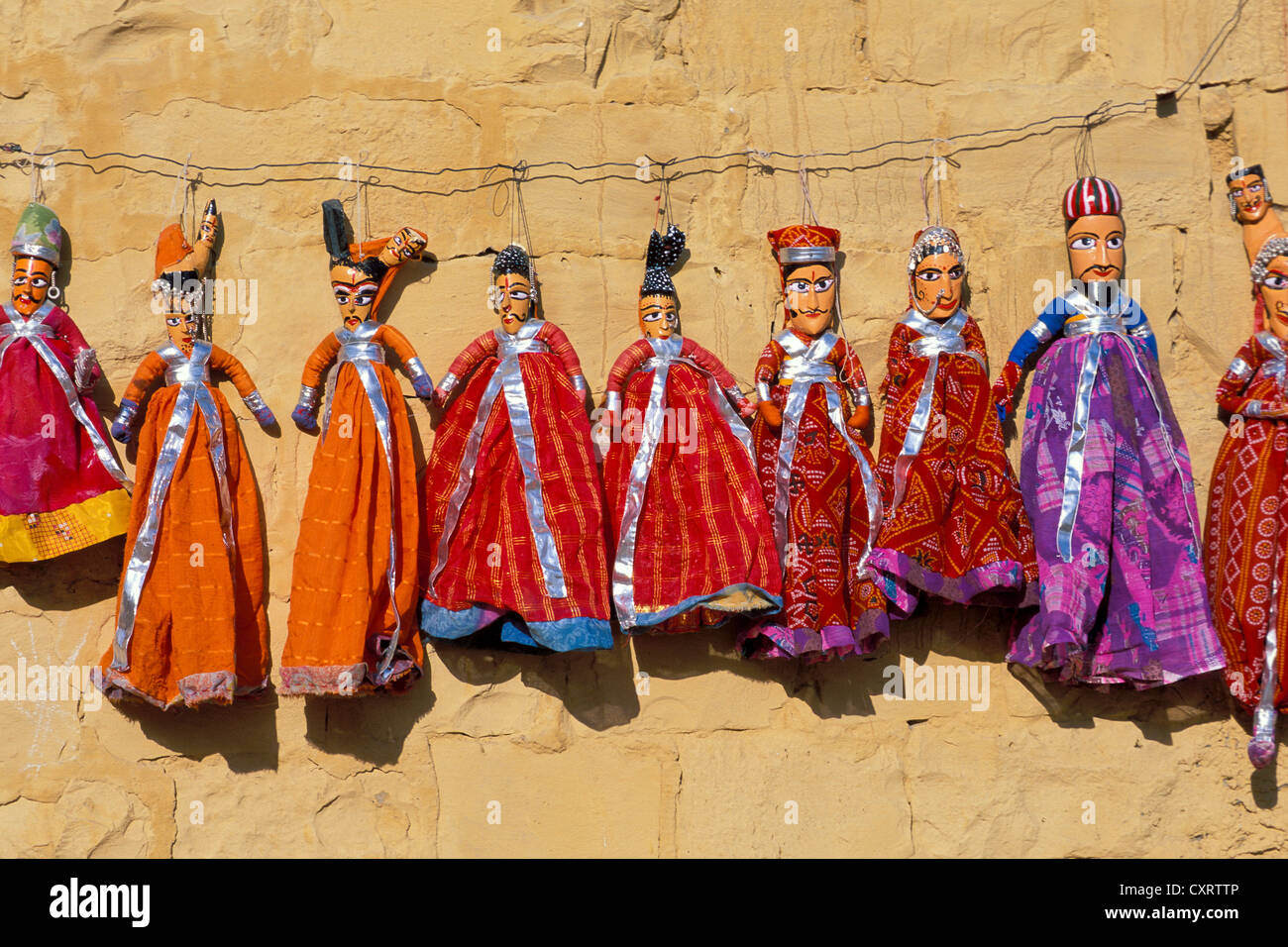 Bambole tradizionali dal nord del Rajasthan sospesa sul filo di fronte un color miele, parete Jaisalmer, Rajasthan, India, Asia Foto Stock