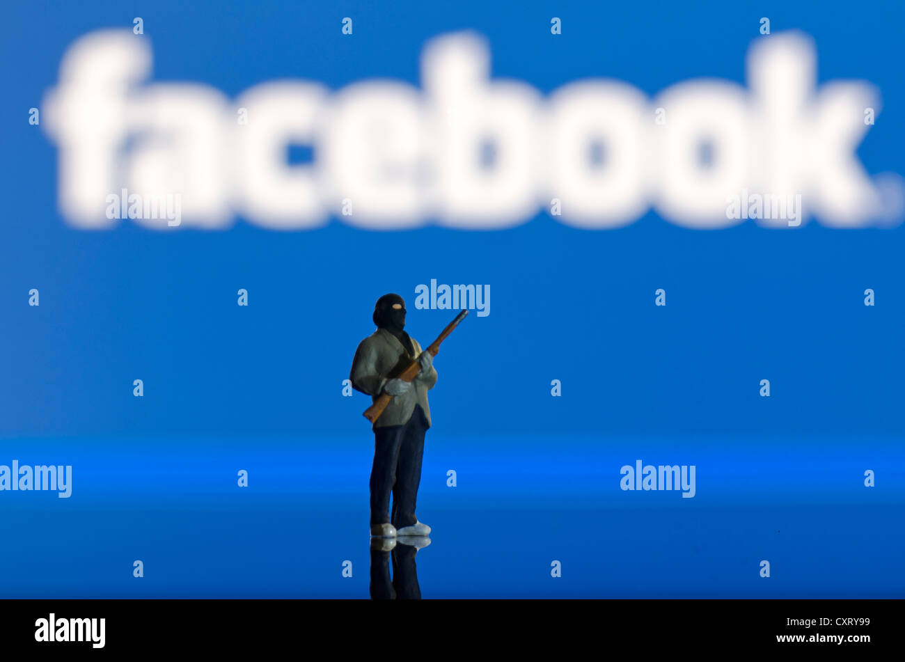 Di islamisti che porta un'arma, miniaturizzato figura in piedi di fronte ad una offuscata logo di Facebook, immagine simbolica Foto Stock