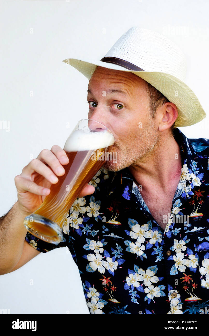 Uomo che indossa un cappello di paglia e una camicia hawaiana di bere birra di grano Foto Stock