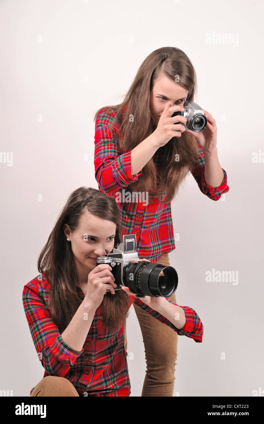 Gemelle holding telecamere, uno tenendo un Pentacon sei medio formato telecamera analogica, l'altra azienda una fotocamera digitale Foto Stock