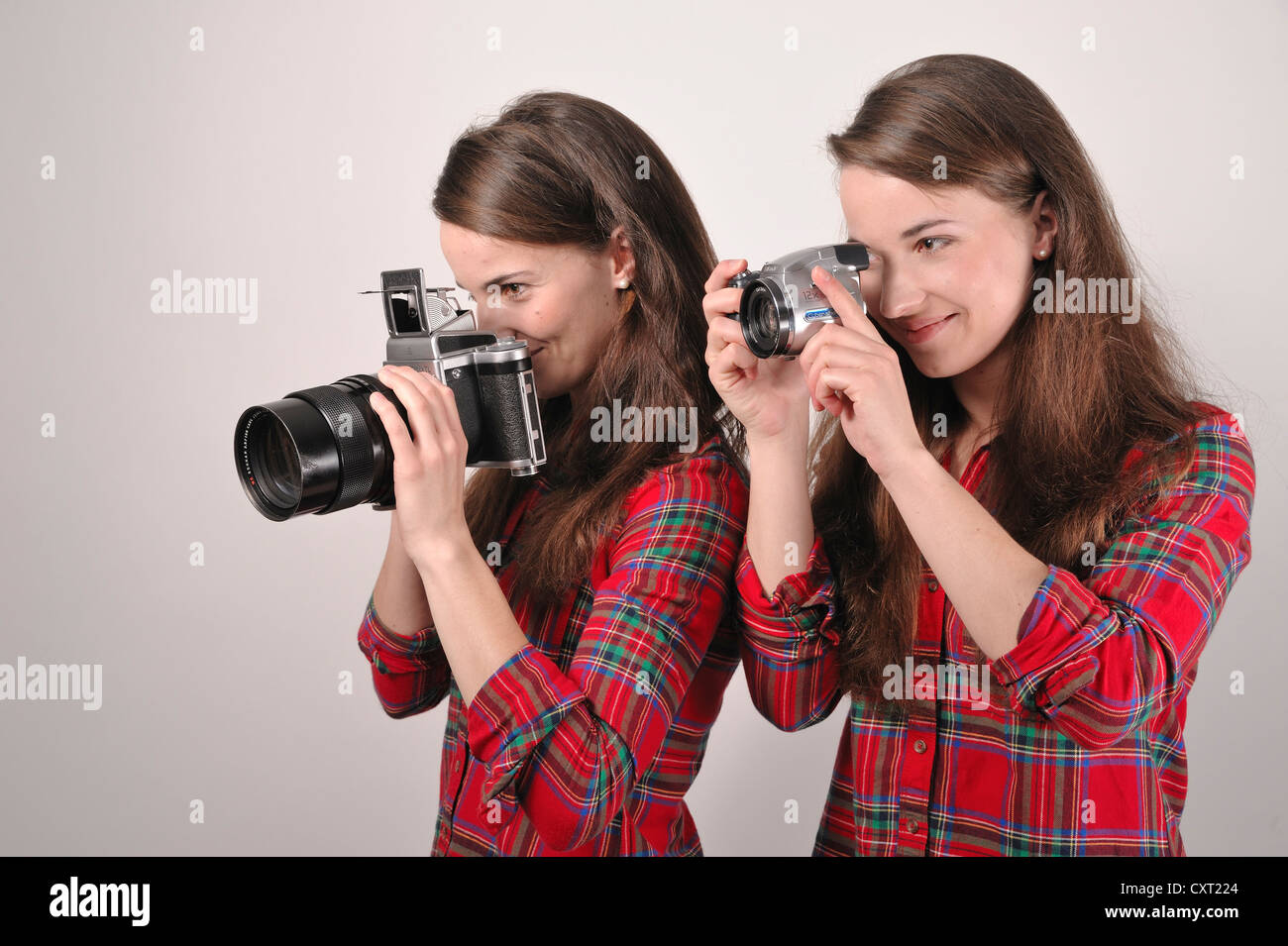 Gemelle holding telecamere, uno tenendo un Pentacon sei medio formato telecamera analogica, l'altra azienda una fotocamera digitale Foto Stock