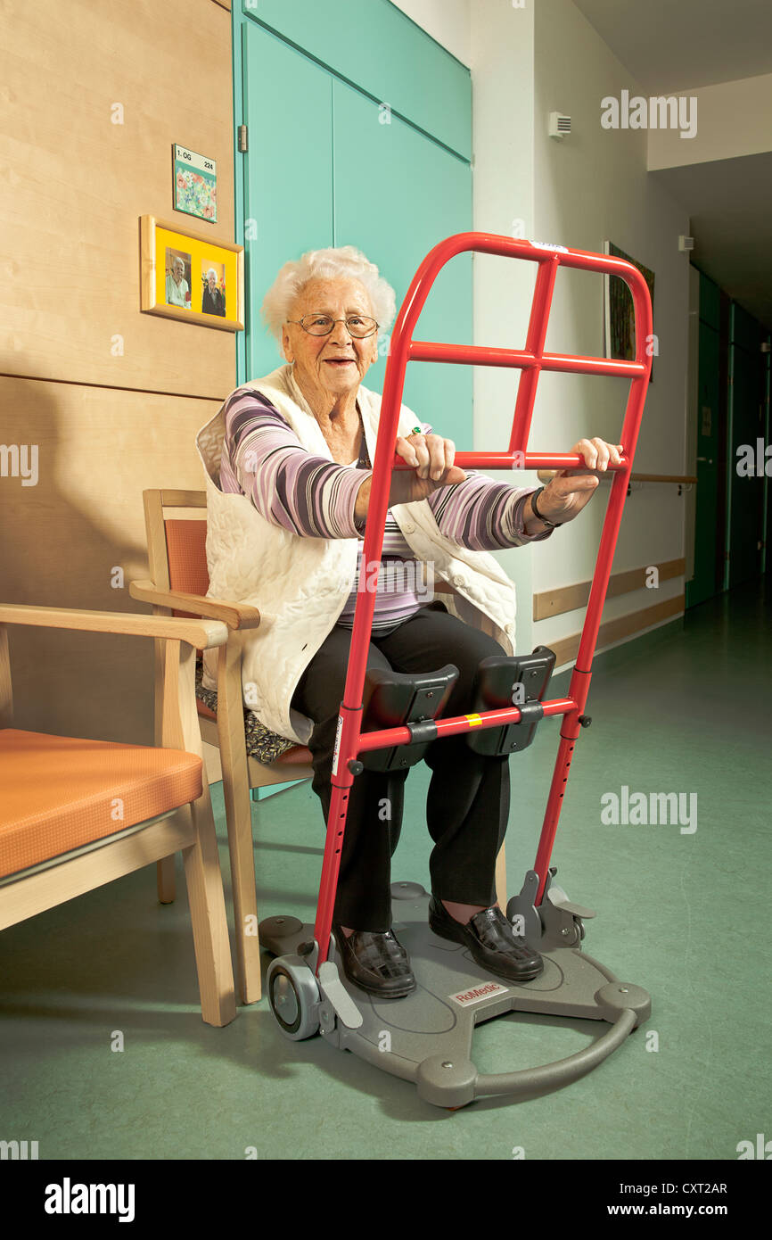 Donna anziana con un aiuto per alzarsi, la casa di cura, la riabilitazione Foto Stock