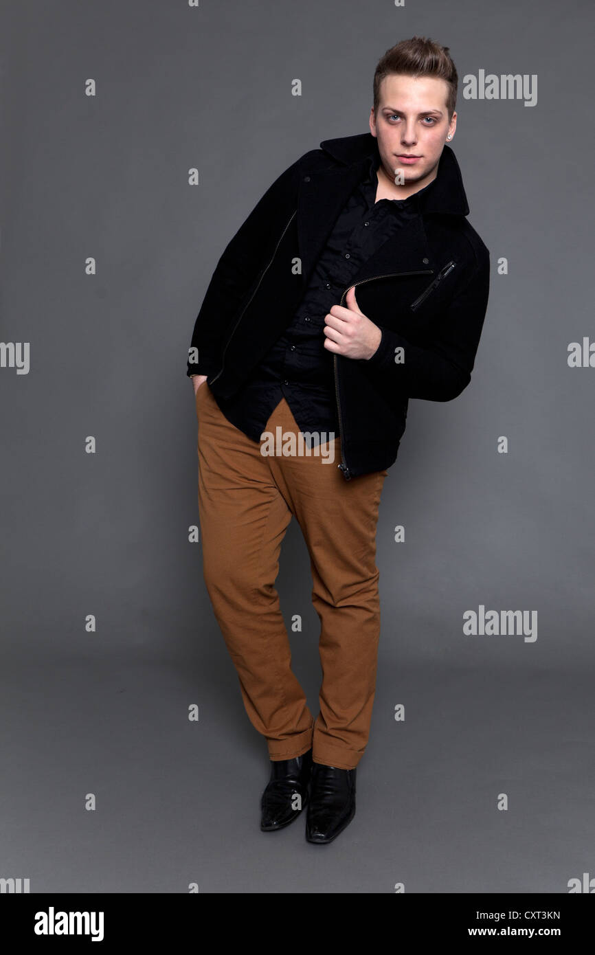 Giovane uomo in una giacca nera e pantaloni marrone Foto stock - Alamy