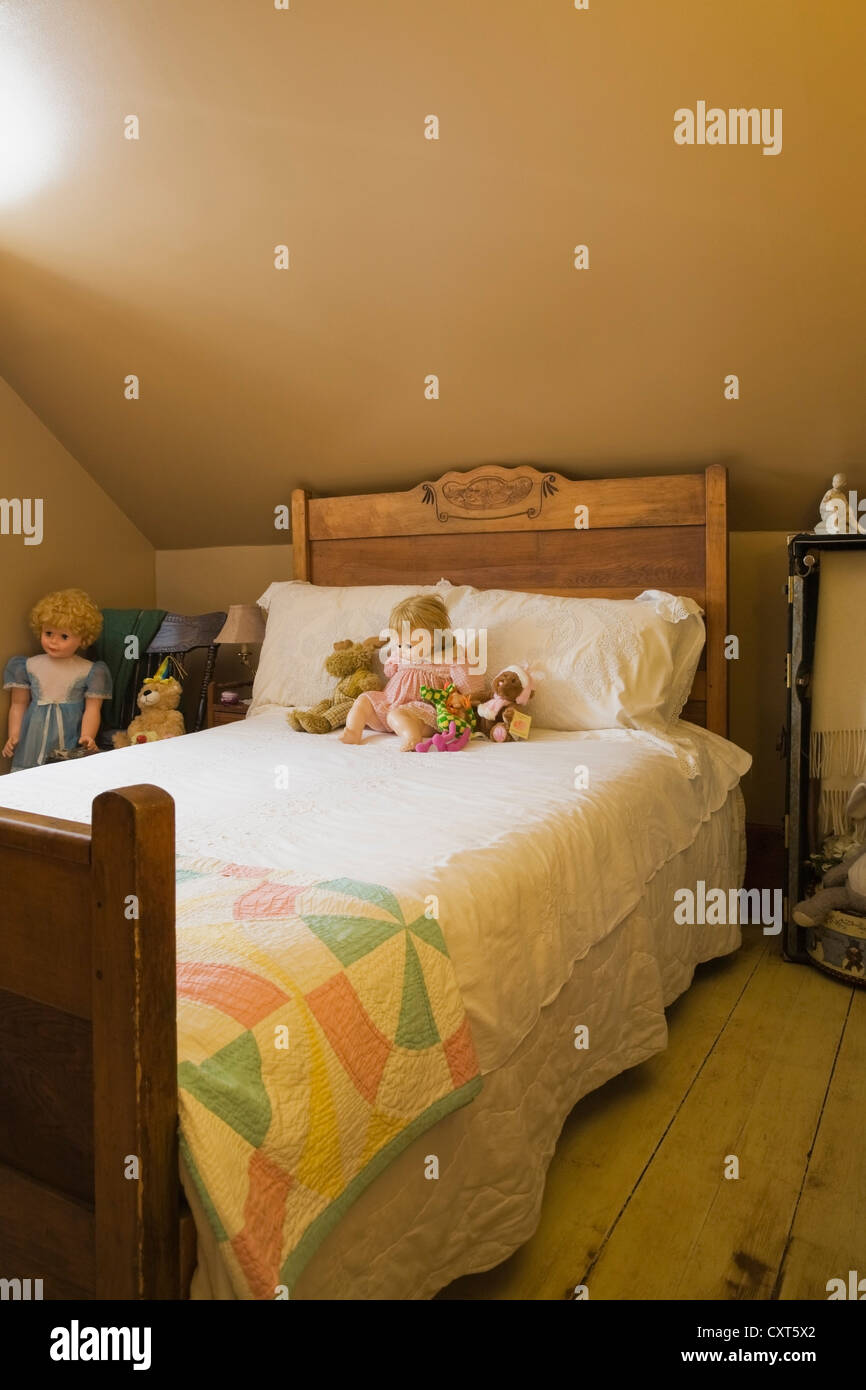 Antico letto singolo con bambole del bambino in una camera da letto sul pavimento del piano superiore di un vecchio Canadiana in stile cottage in pietra di cava Foto Stock