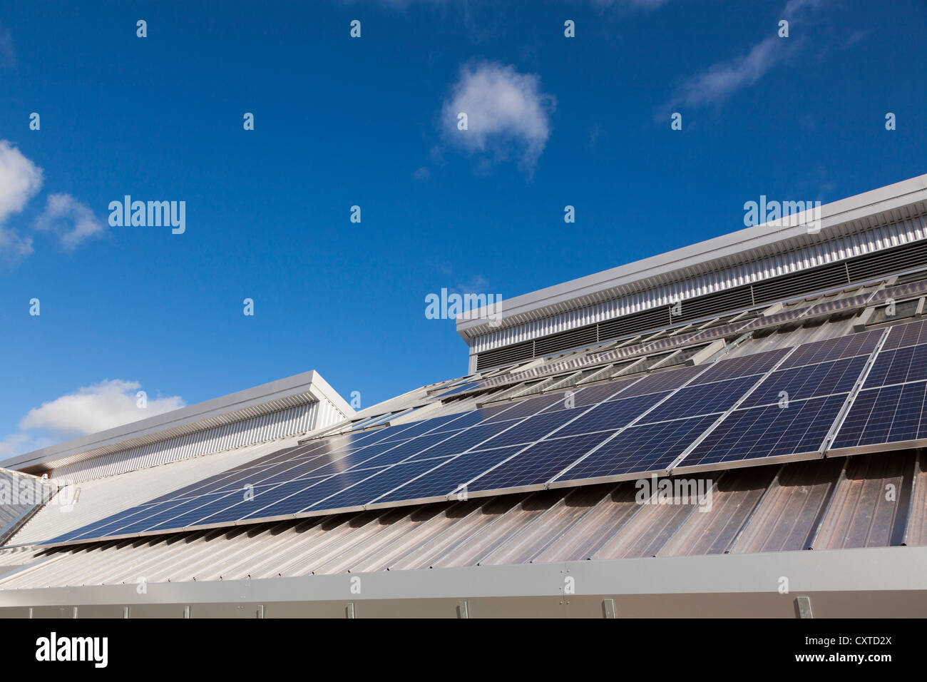 Pannelli solari sul tetto della scuola contro il cielo blu nella luce del sole Foto Stock