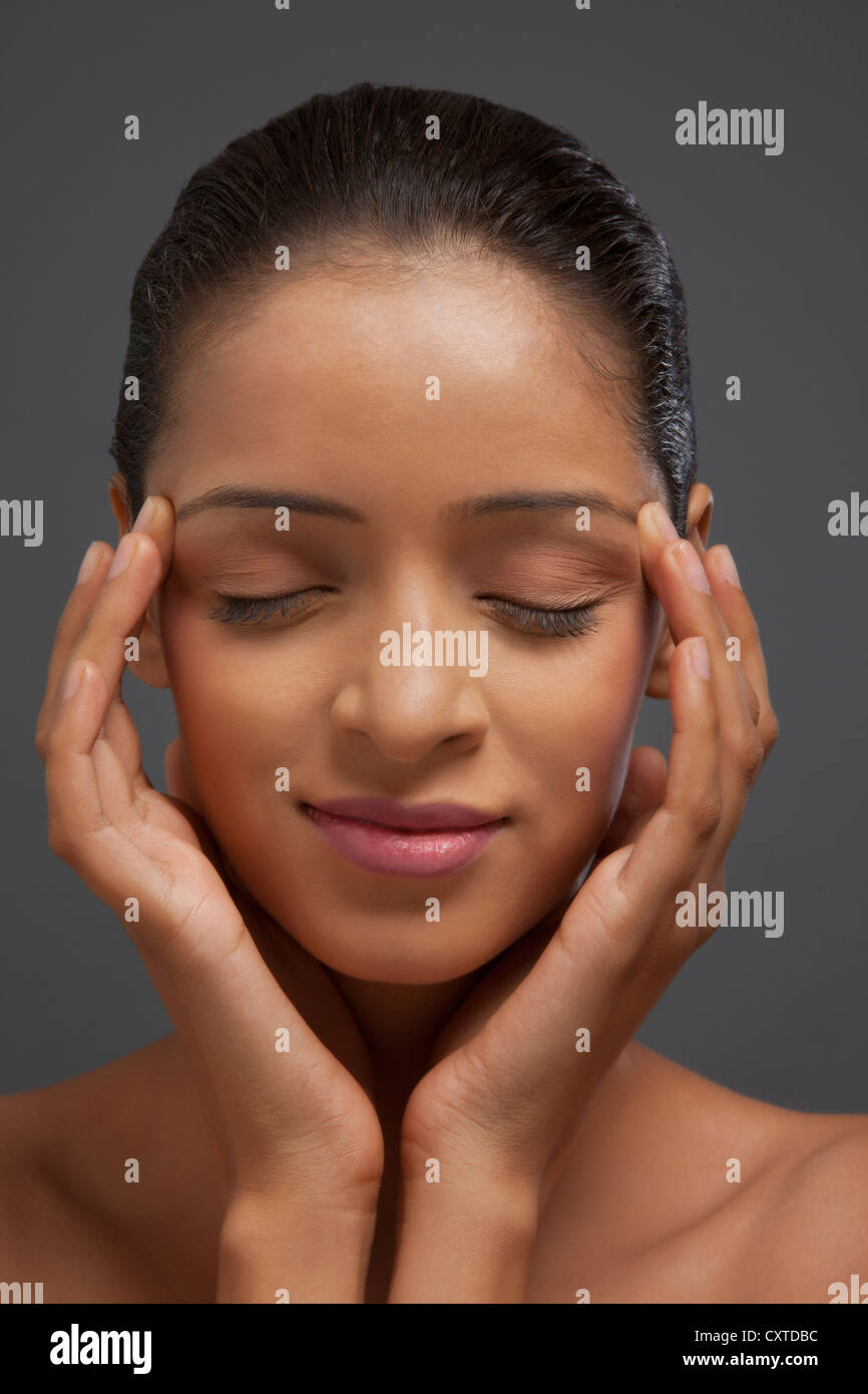 Close-up di donna con gli occhi chiusi e le dita sulle tempie Foto Stock