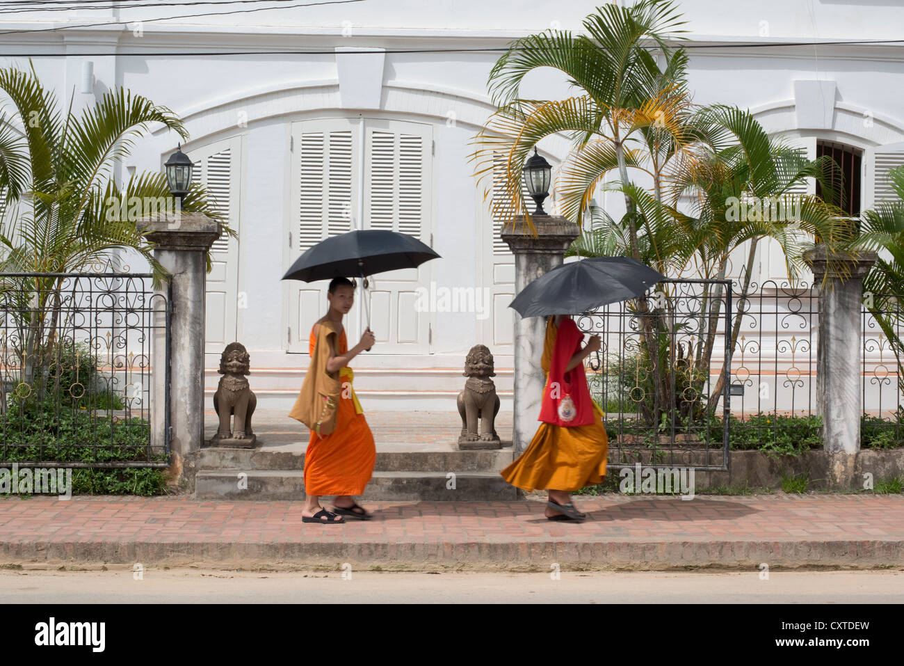 Due monaci passano da un edificio in stile coloniale Francese. Luang Prabang, Laos Foto Stock