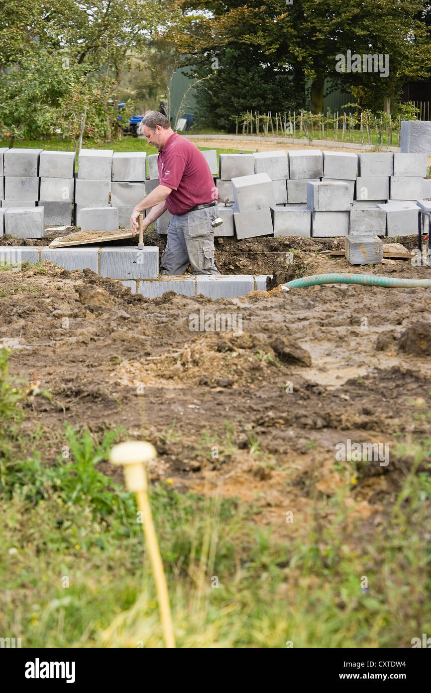 Muratore in posa del calcestruzzo il blocco su un Regno Unito sito in costruzione Foto Stock