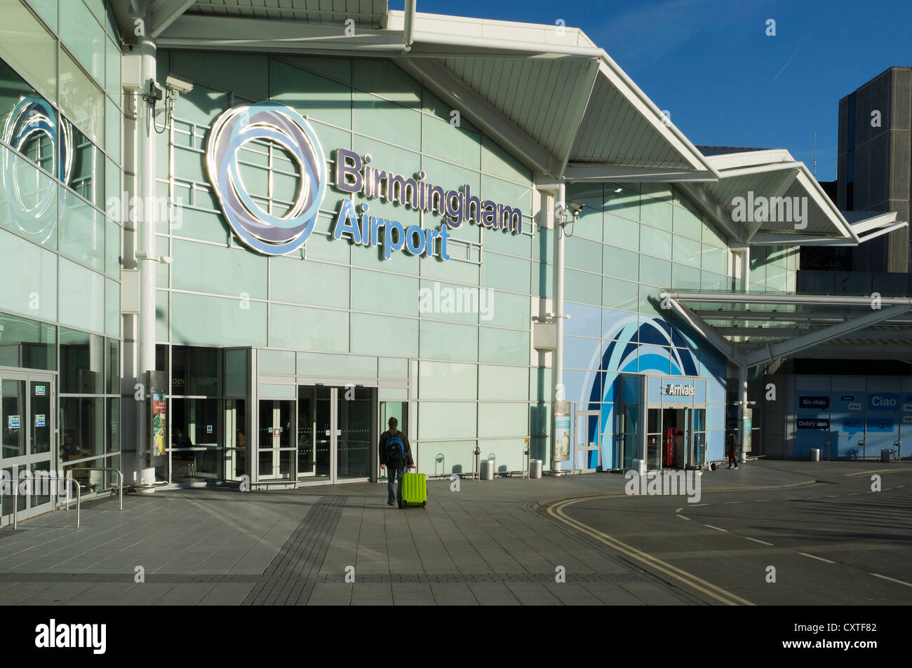 dh Aereoporti terminal edificio BIRMINGHAM AIRPORT UK Passenger con valigia Ingresso esterno agli arrivi Foto Stock