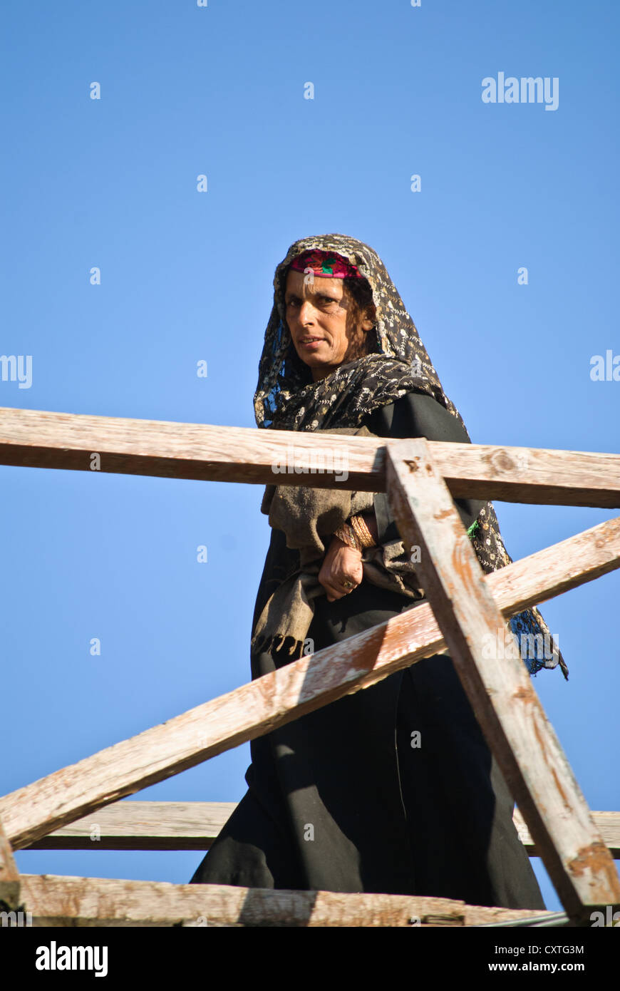 Una donna locale attraversando un ponte in legno Pahalgam, Kashmir Foto Stock