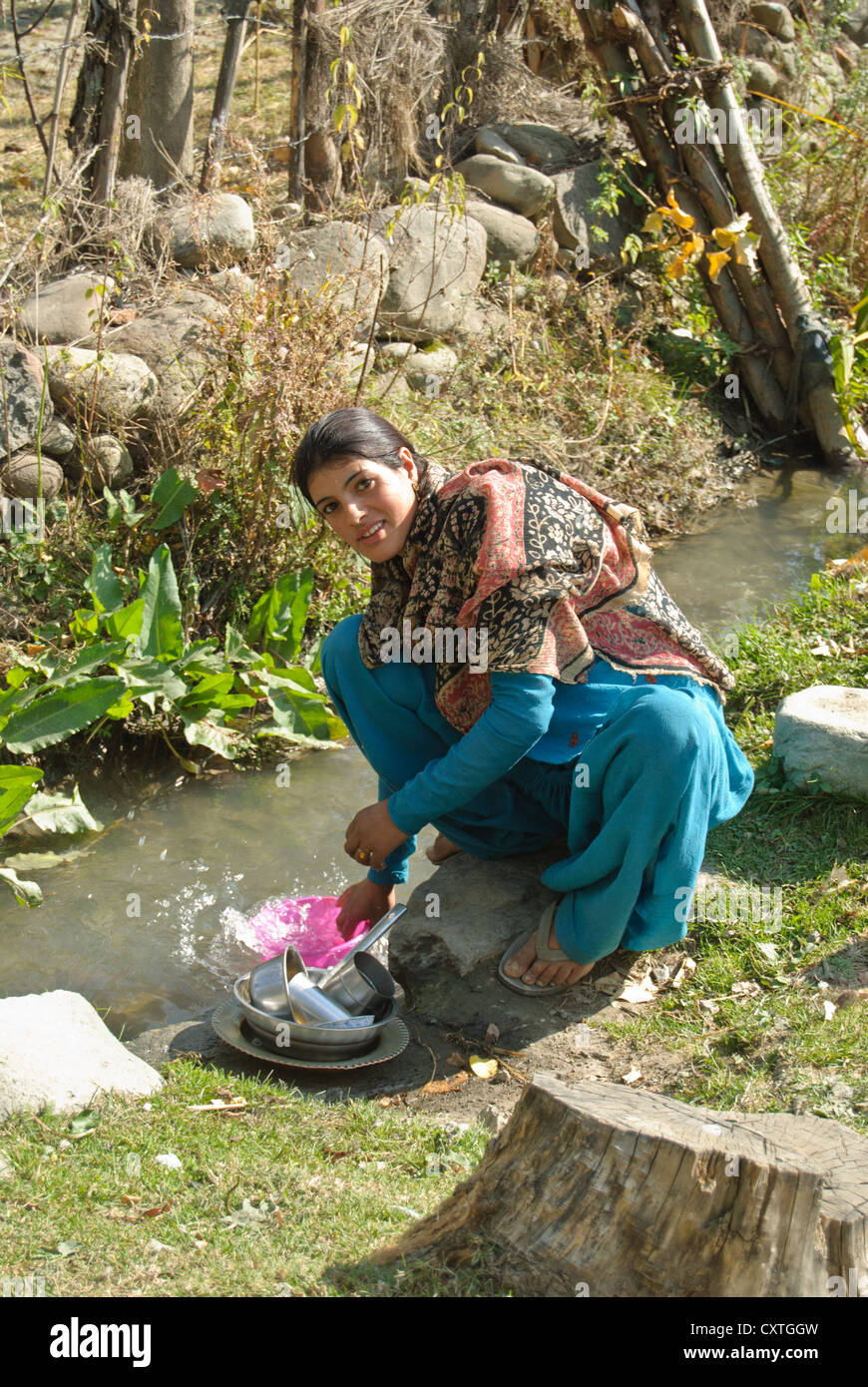 Un abitante locale lavaggio piatti in una piccola corrente passante in un villaggio nei pressi di Pahalgam Foto Stock