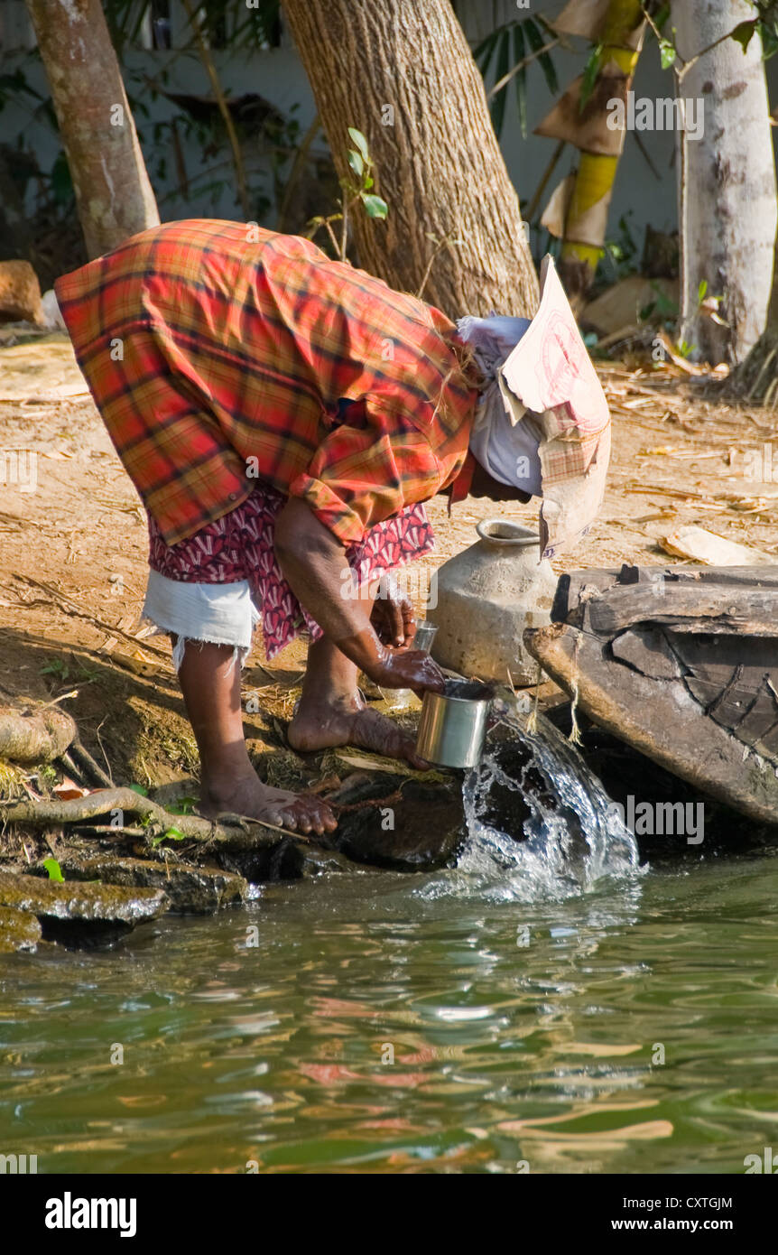 Verticale di una persona indiano con un ripiego hat di cartone facendo il loro lavaggio fino al fiume. Foto Stock