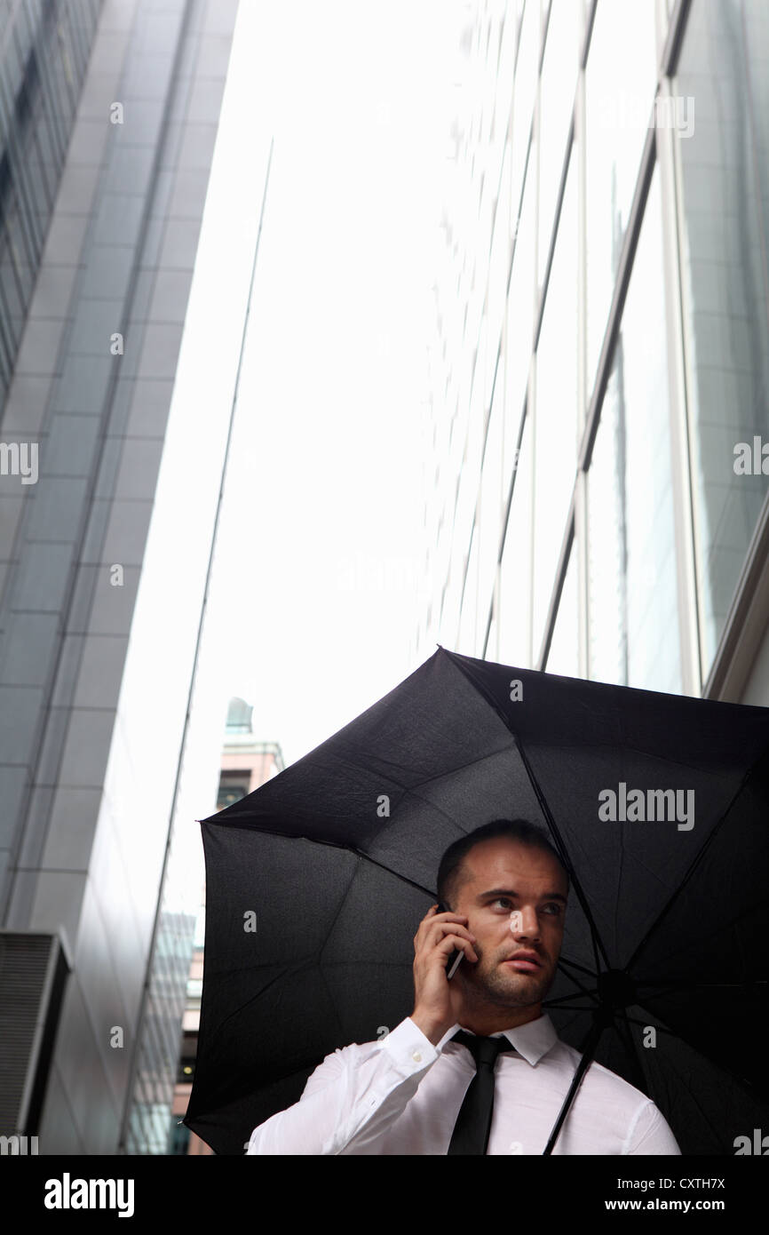 Imprenditore camminare sotto ombrellone Foto Stock
