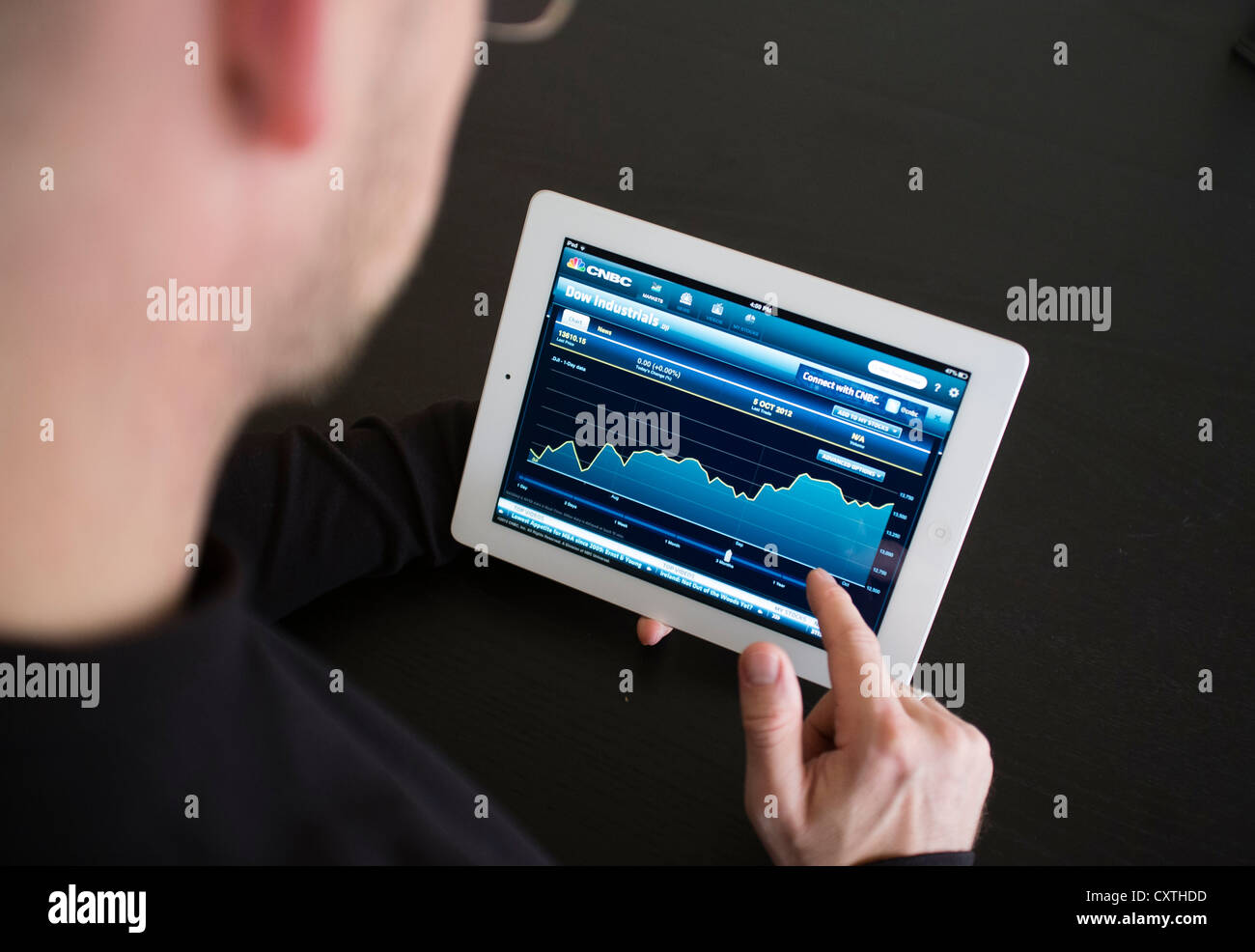 L'uomo controllo prestazioni del Dow Jones stock a prezzi di mercato su iPad3 computer tablet Foto Stock