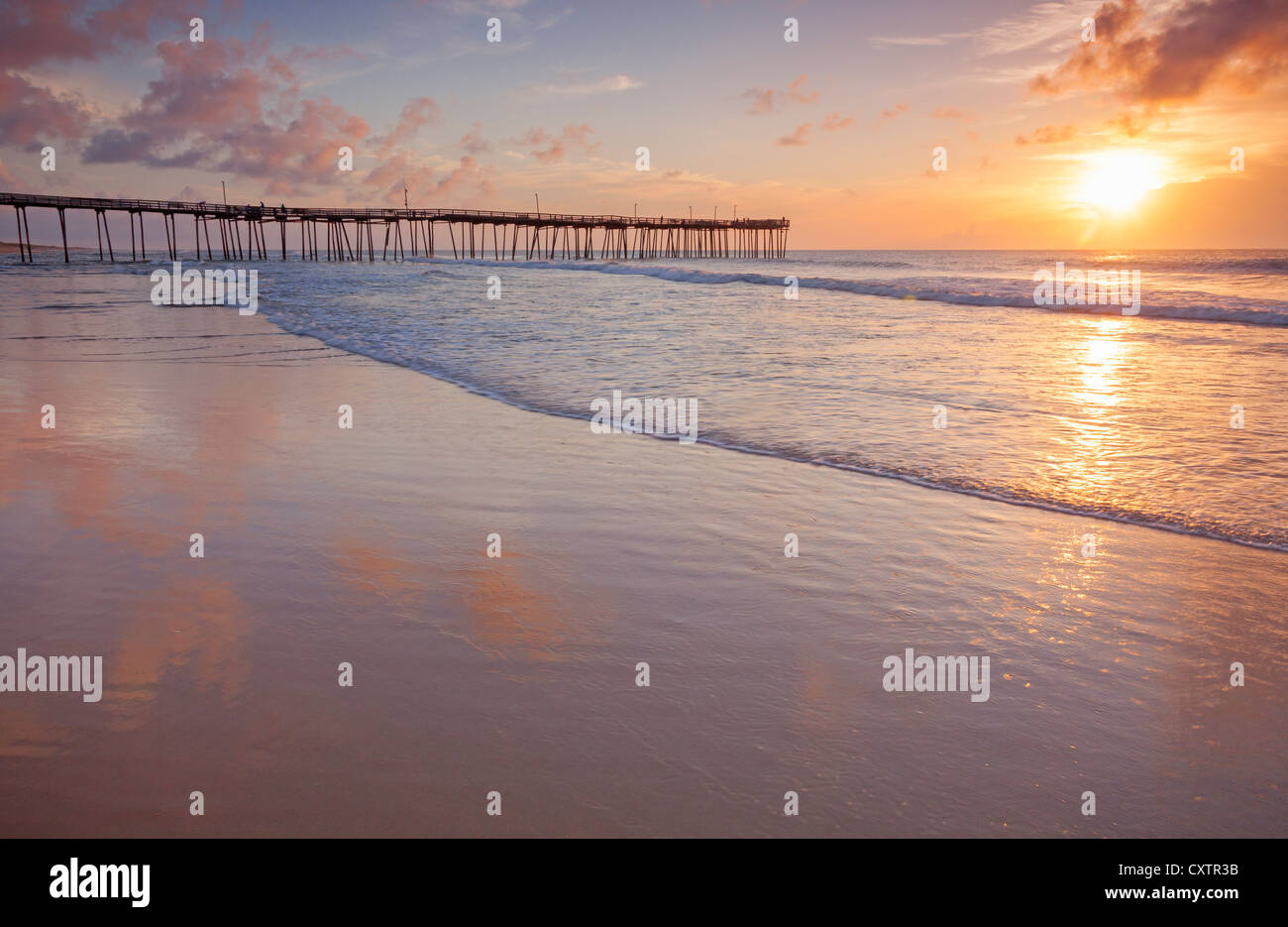 Cape Hatteras National Seashore, Avon, North Carolina Sunrise e riflessioni sulla spiaggia con Avon pesca del molo a distanza Foto Stock