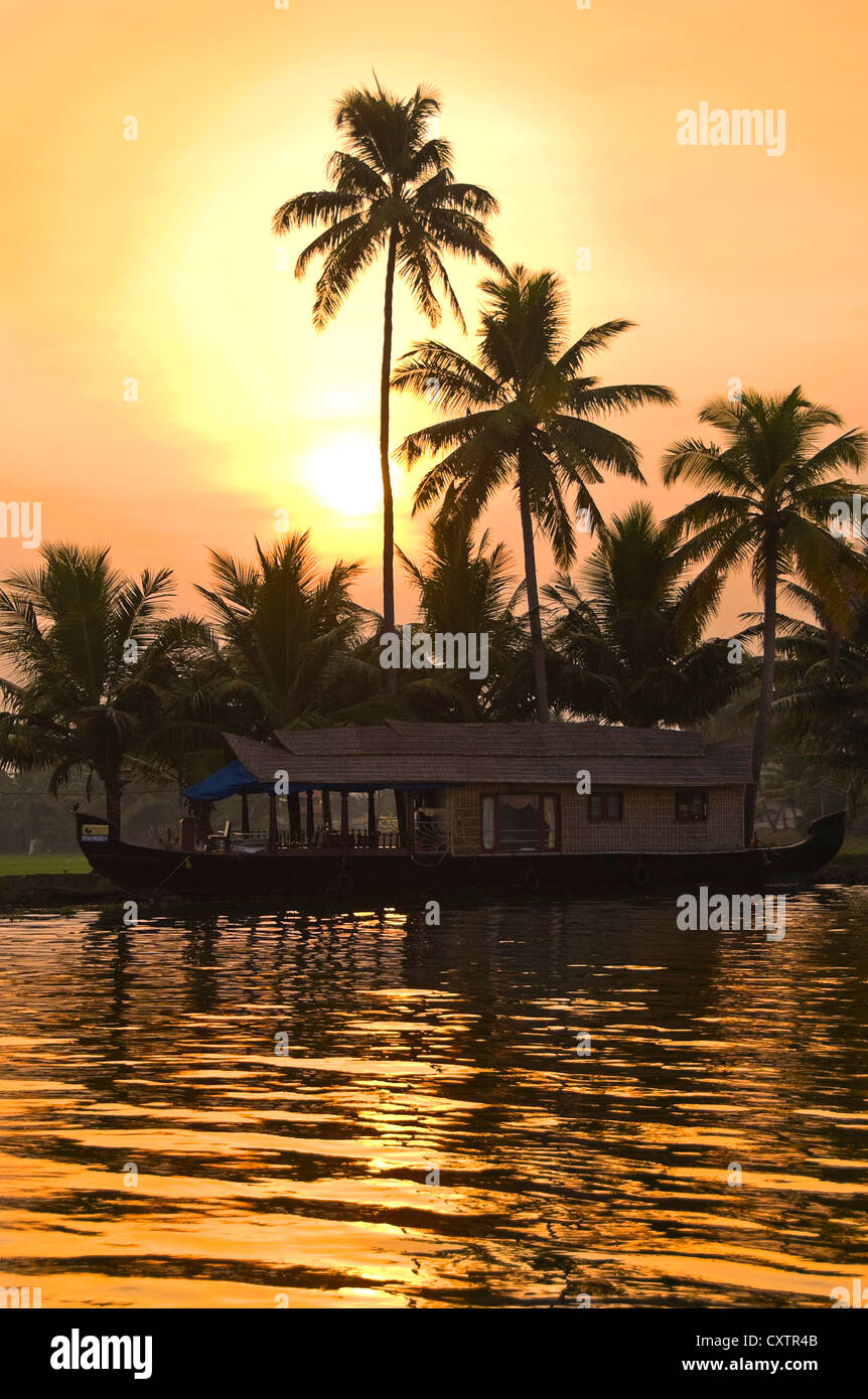 Vista verticale di una tradizionale casa in legno barca, kettuvallam, al tramonto nelle lagune del Kerala. Foto Stock