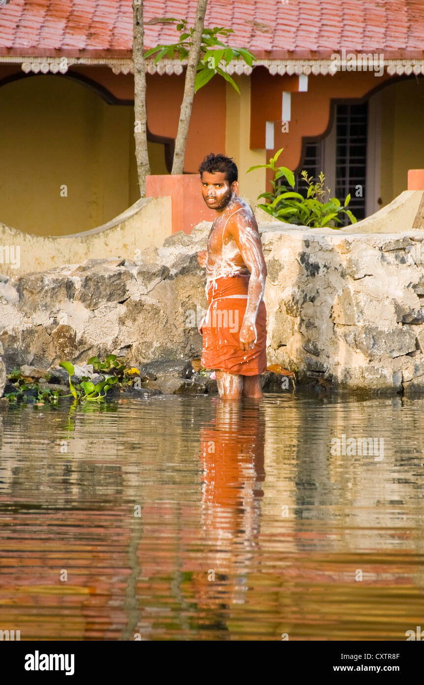 Ritratto verticale di un uomo il lavaggio stesso dal lato del fiume in Kerala. Foto Stock