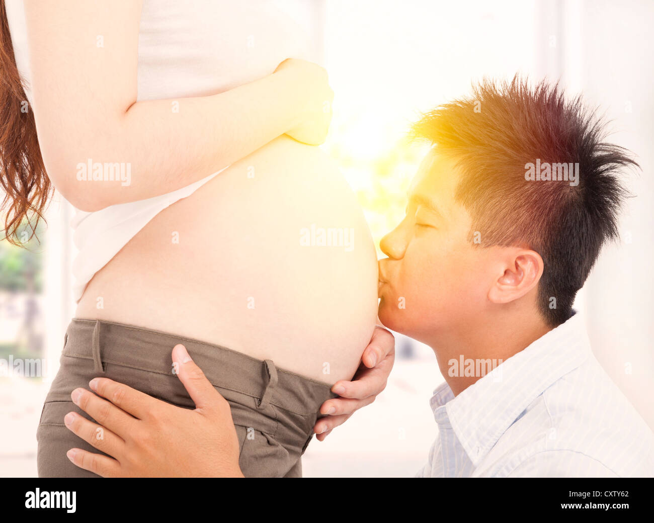 Padre asiatici baciando la sua moglie incinta la pancia al mattino Foto Stock
