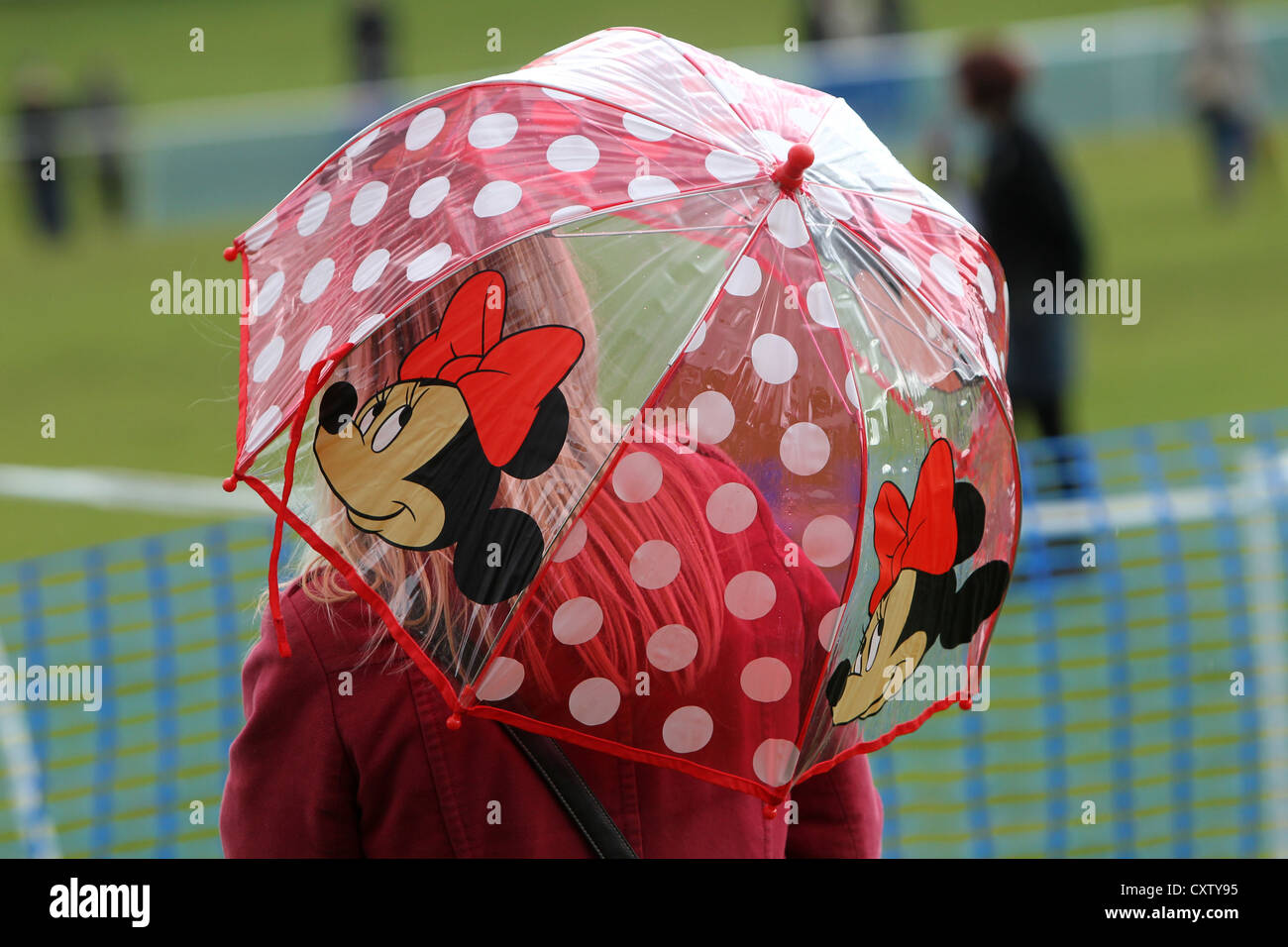 Una signora tenendo un Minnie Mouse ombrello in un parco a Hove, East Sussex, Regno Unito. Foto Stock