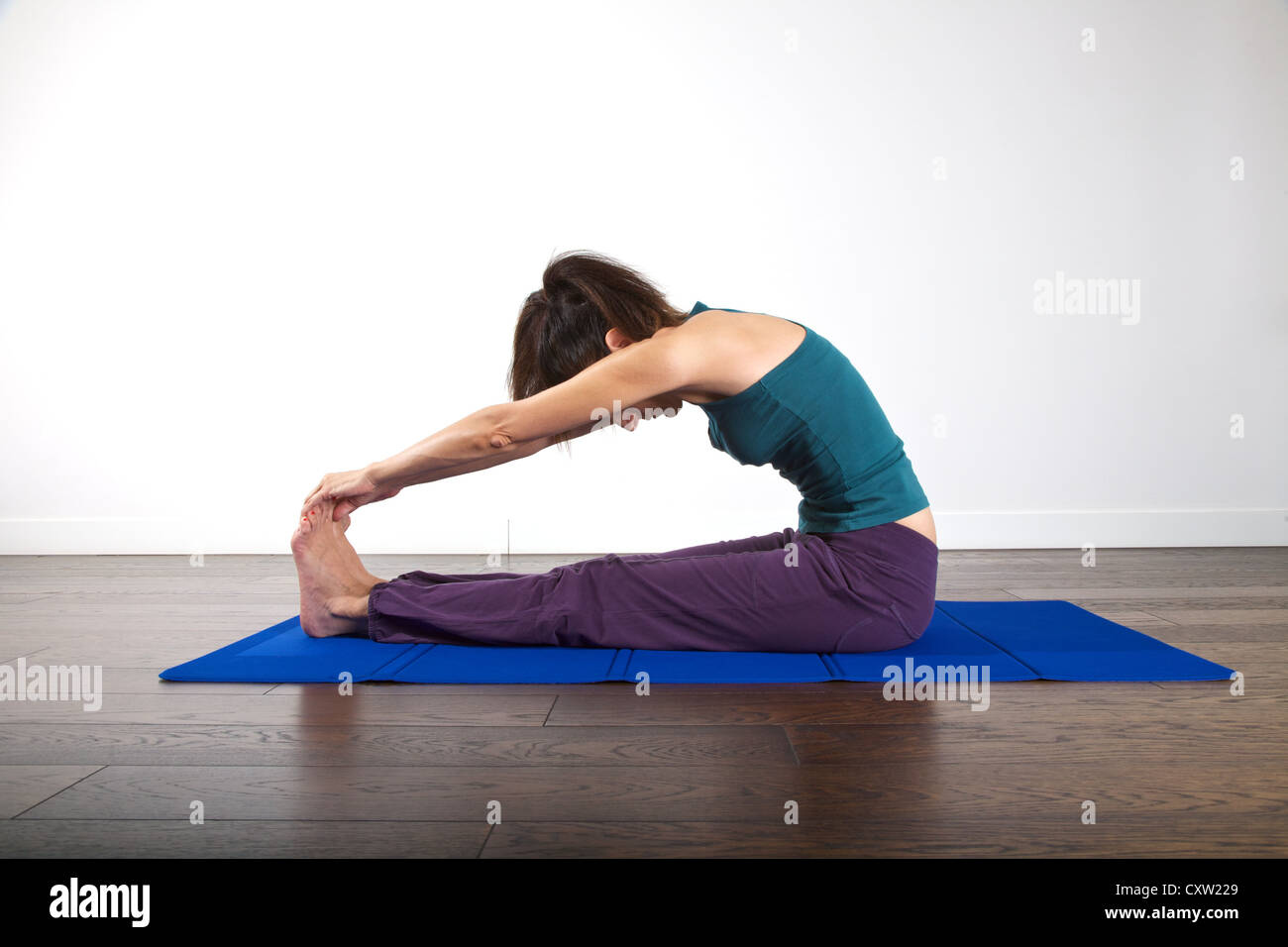 La donna sta facendo ginnastica sul tappetino su sfondo bianco Foto Stock