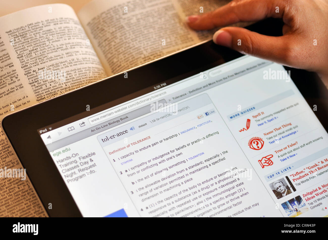 Online Dizionario Webster su iPad e una copia cartacea al di sotto di esso Foto Stock