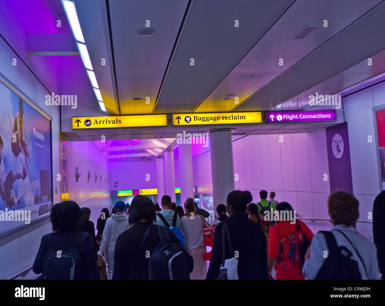 ARRIVI passeggeri Airline che arrivano al passaggio pedonale dell'aeroporto di Heathrow illuminato colori calmanti per gli arrivi e le aree di ritiro bagagli Foto Stock
