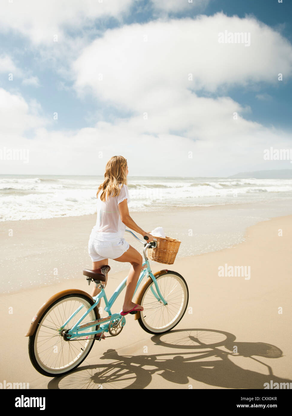 La donna caucasica Bicicletta Equitazione sulla spiaggia Foto Stock