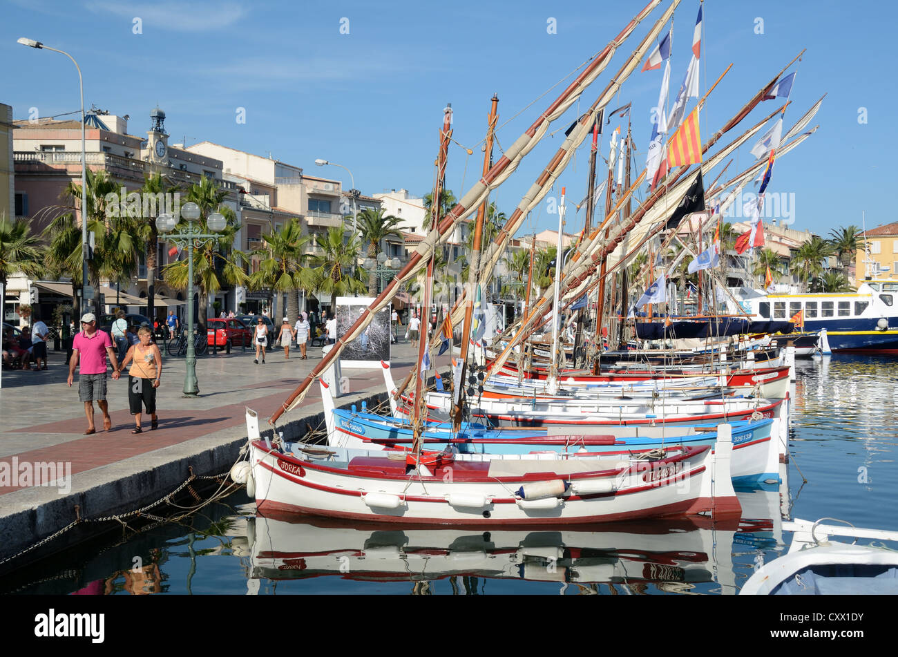 I turisti camminano lungo Quayside accanto a colorate barche in legno, noto come Pointus, nel porto o porto di Sanary-sur-Mer Var Provence France Foto Stock