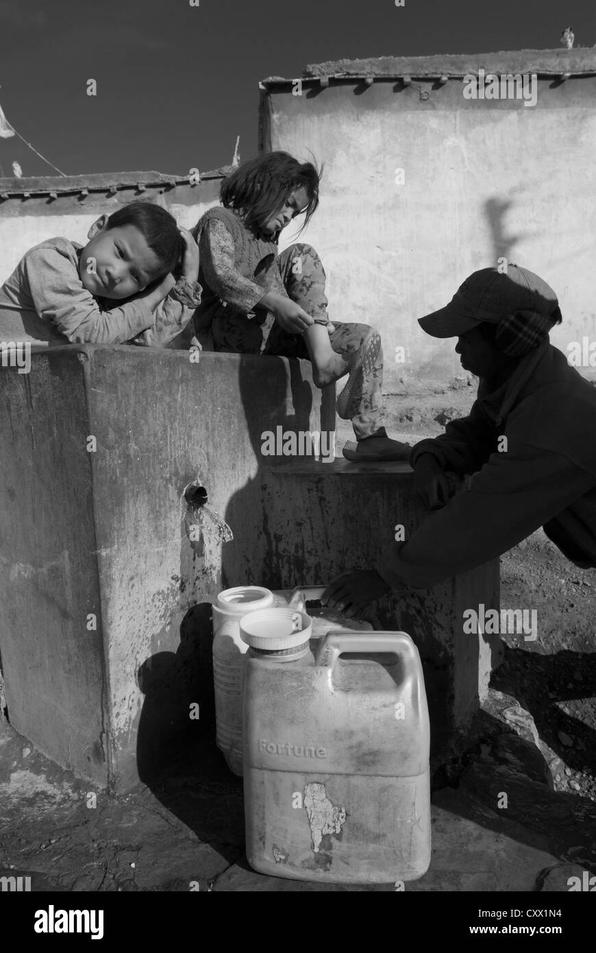 Tre i bambini riempiono contenitori di acqua nel villaggio di Kibber, Spiti, India settentrionale Foto Stock