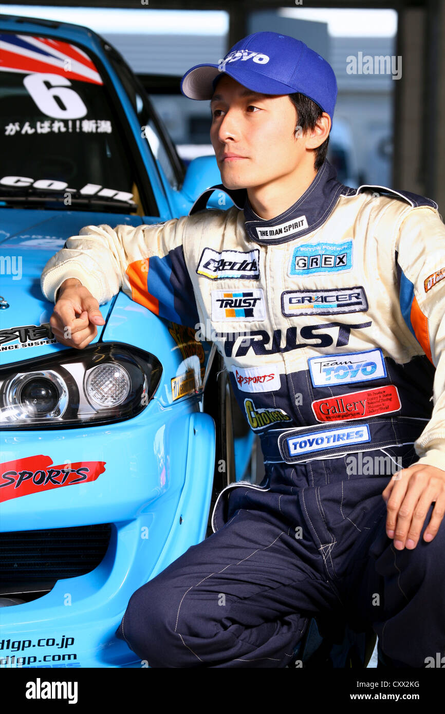 Ritratto di race driver poste con auto in garage Foto Stock