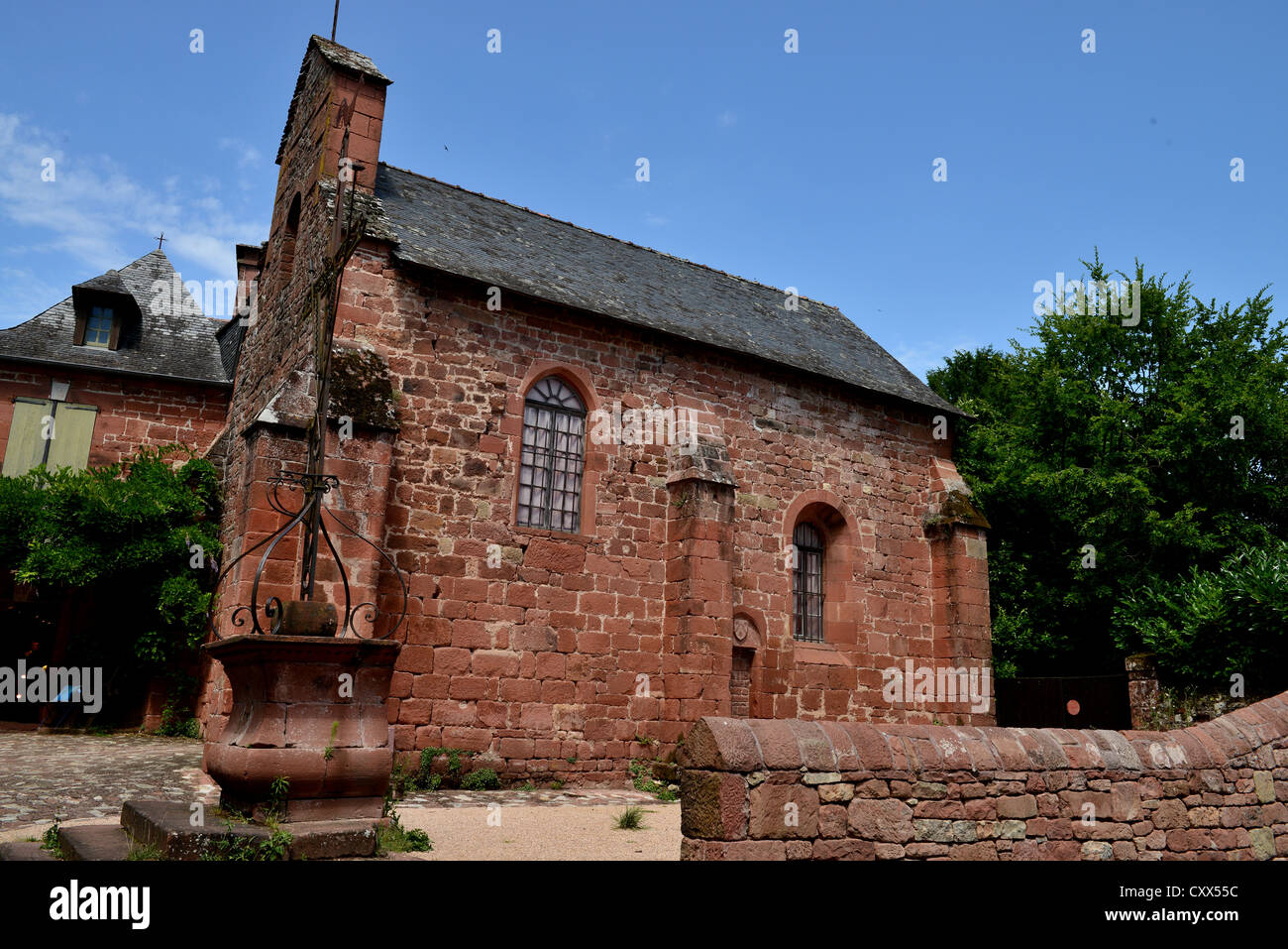 Villaggio di Collonges la Rouge. Corrèze Limousin Francia Chiesa Rossa con Ben. Cielo blu; messa domenicale villaggio chiesa Foto Stock