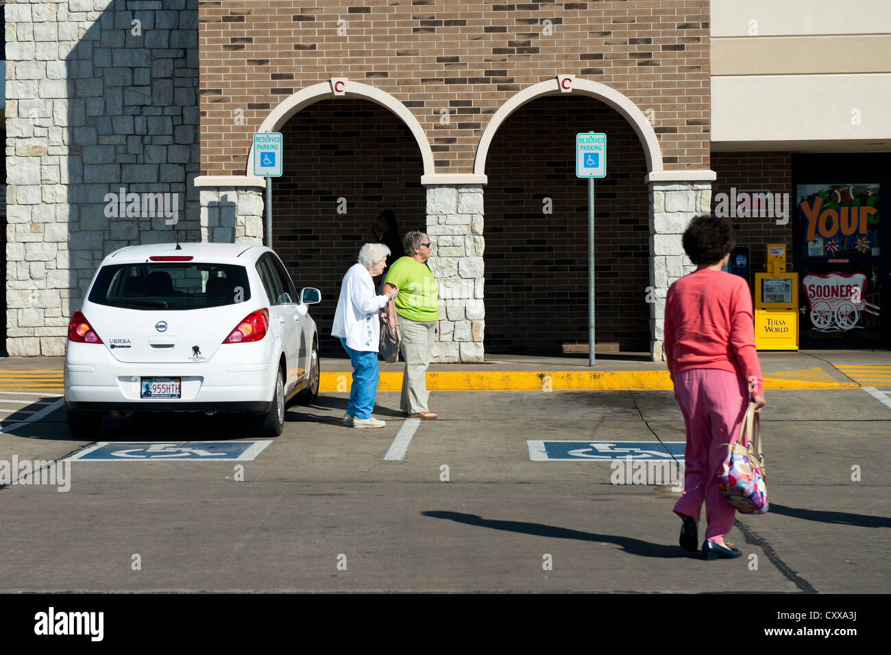 Una donna obesa aiuta una donna anziana dopo aver parcheggiato in un parcheggio per disabili posto presso un supermercato in Oklahoma, Stati Uniti. Stati Uniti d'America. Foto Stock