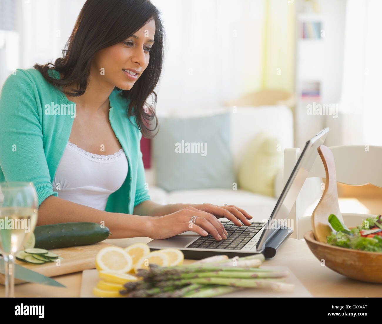 Razza mista donna utilizzando laptop in cucina Foto Stock