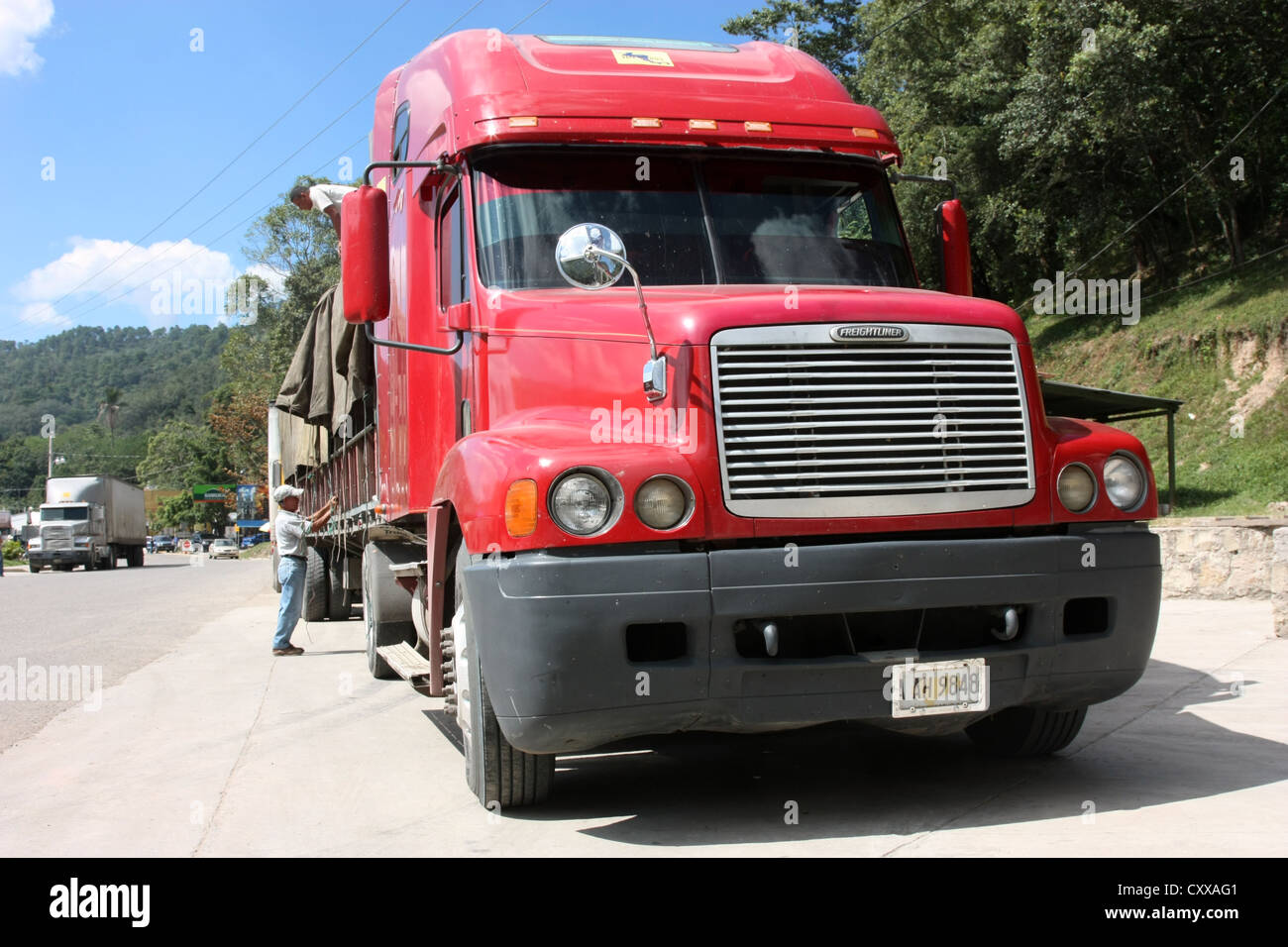 Il conducente assicura il carico di un semirimorchio Freightliner dell'Honduran al confine con l'Honduran, El Salvador, America Centrale Foto Stock