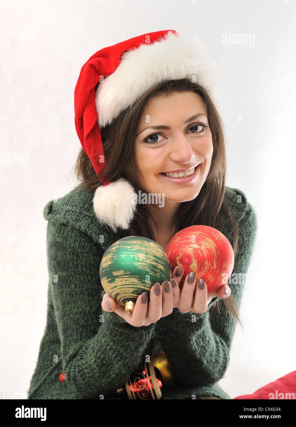 Giovane donna con cappello da Babbo Natale tenendo due baubles di natale Foto Stock