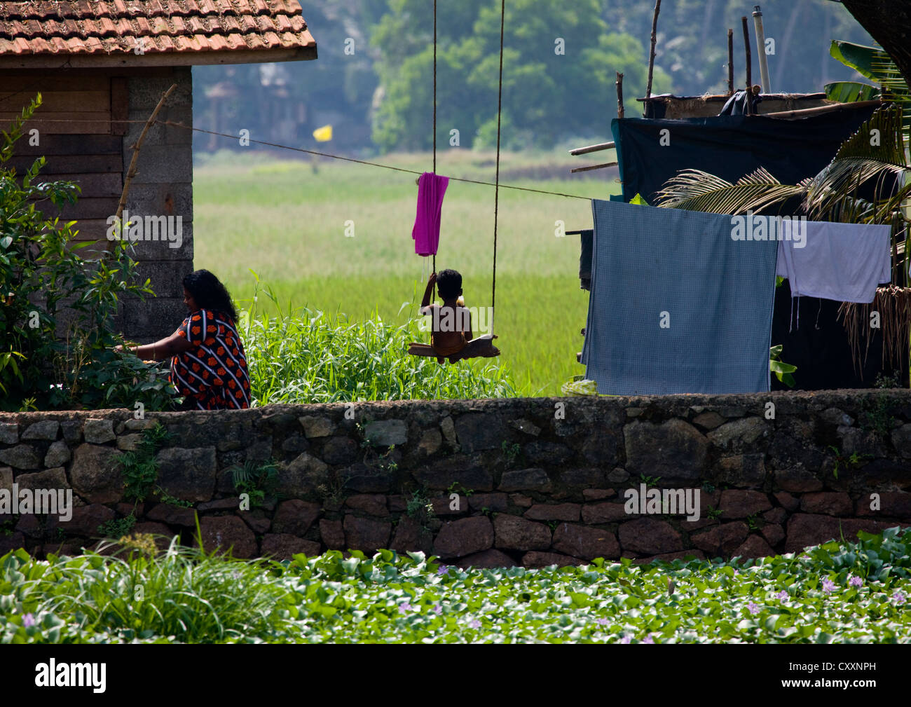 Un giovane bambino seduto su un altalena vicino le lagune del Kerala, Cochin, India Foto Stock