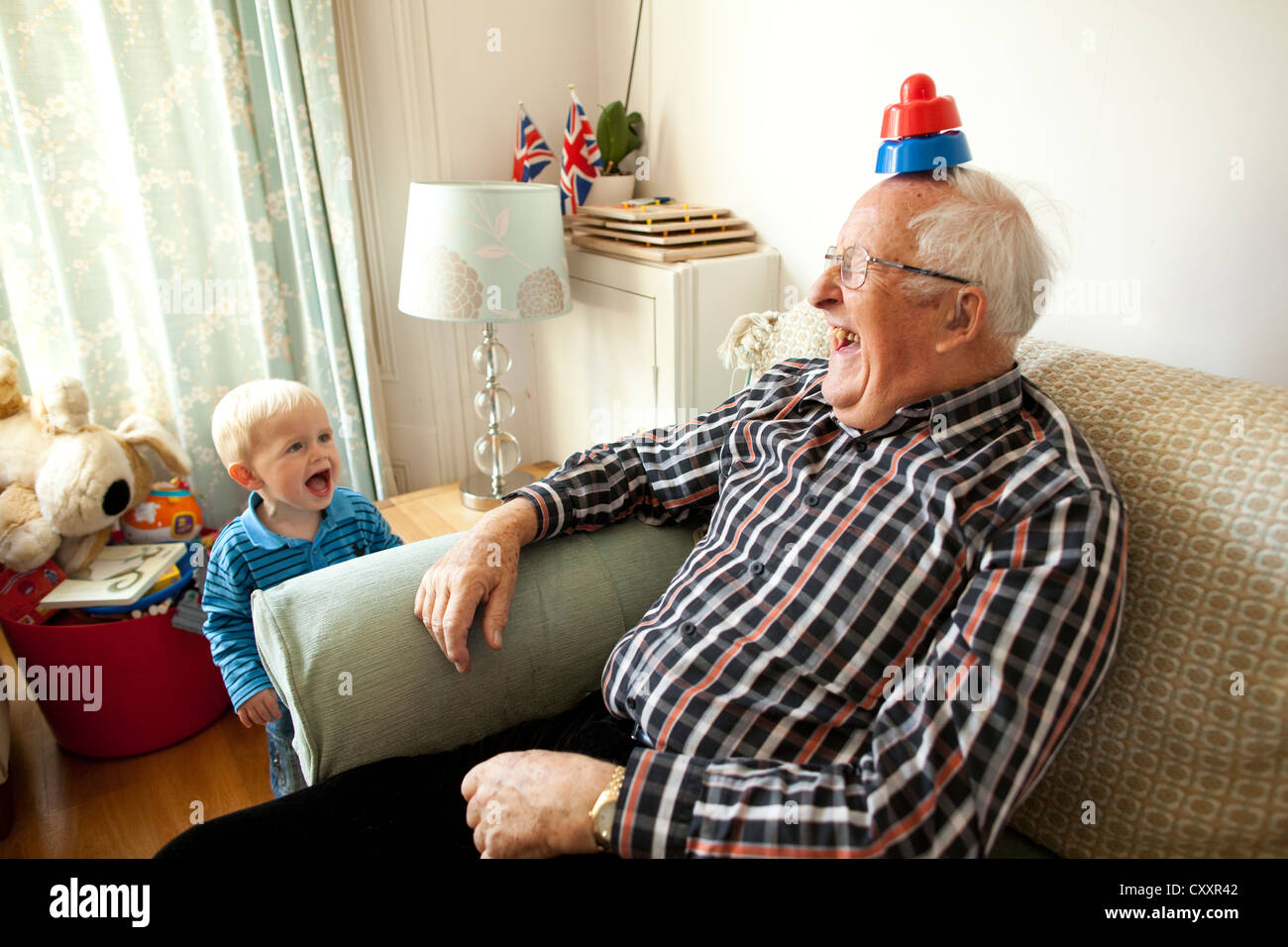 Nonno divertendosi con il nipote in casa nel salotto come più nonni sono avente per prendersi cura dei loro nipoti, REGNO UNITO Foto Stock