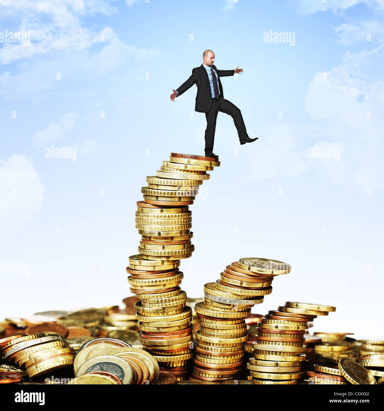L'uomo cerca di equilibrio stesso su pali di monete Foto Stock